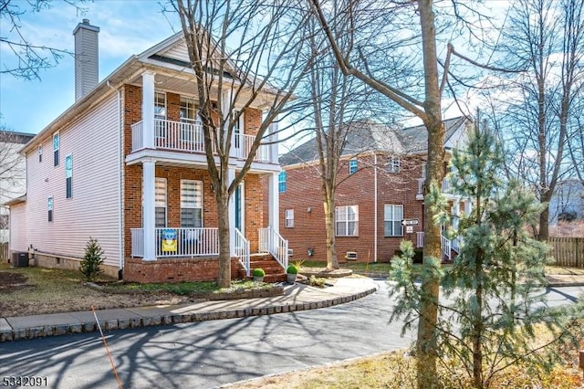 view of front of property with a balcony, a chimney, crawl space, covered porch, and brick siding