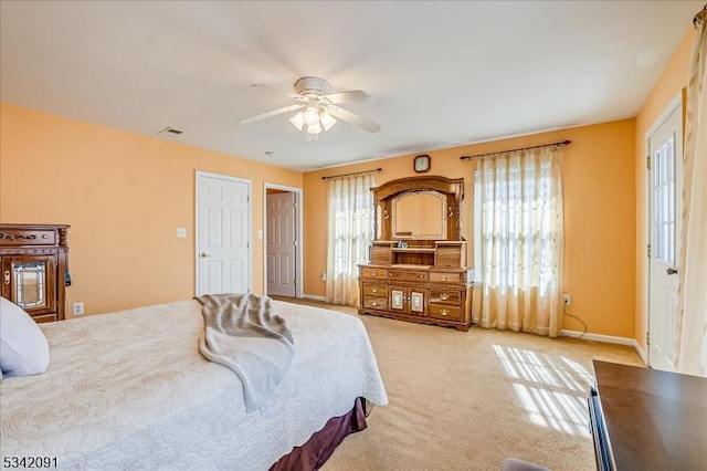 bedroom with a ceiling fan, light colored carpet, visible vents, and baseboards