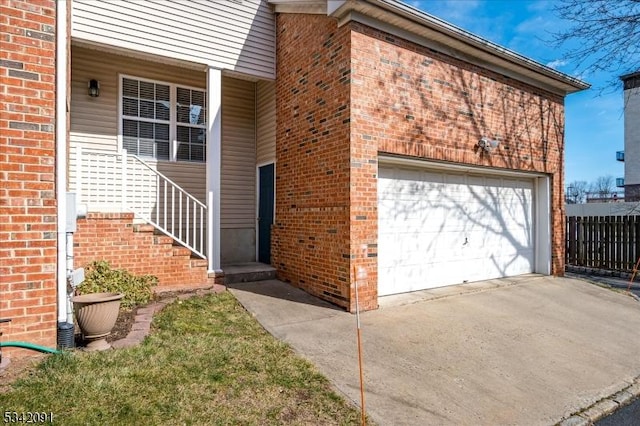 property entrance featuring a garage, fence, concrete driveway, and brick siding