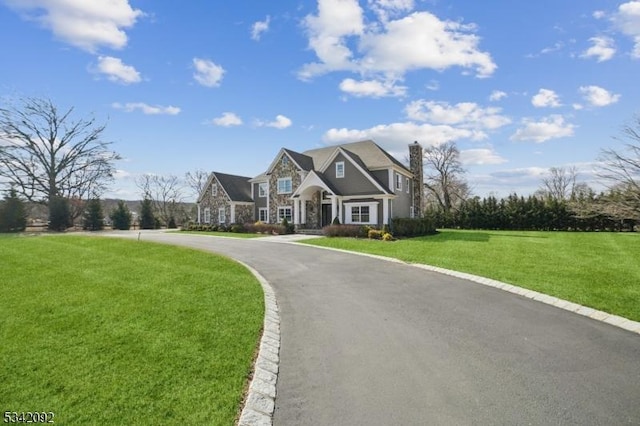 view of front of house with stone siding, a chimney, and a front yard