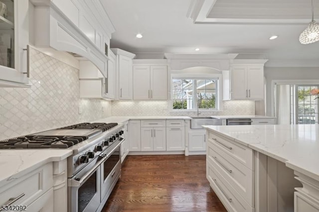 kitchen featuring white cabinets, custom exhaust hood, ornamental molding, and range with two ovens