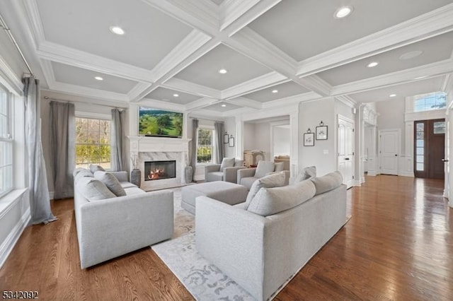 living room featuring coffered ceiling, wood finished floors, beam ceiling, and a healthy amount of sunlight