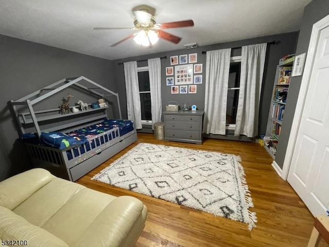 bedroom with ceiling fan, wood finished floors, and visible vents