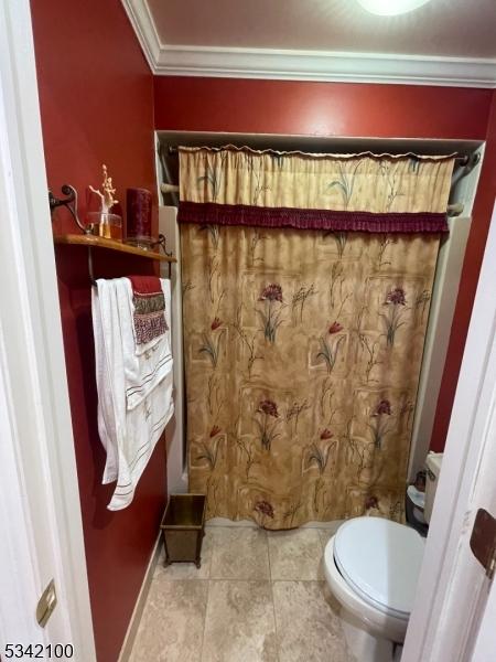 bathroom with ornamental molding, toilet, and tile patterned floors