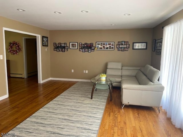 living room with a baseboard radiator, baseboards, and wood finished floors