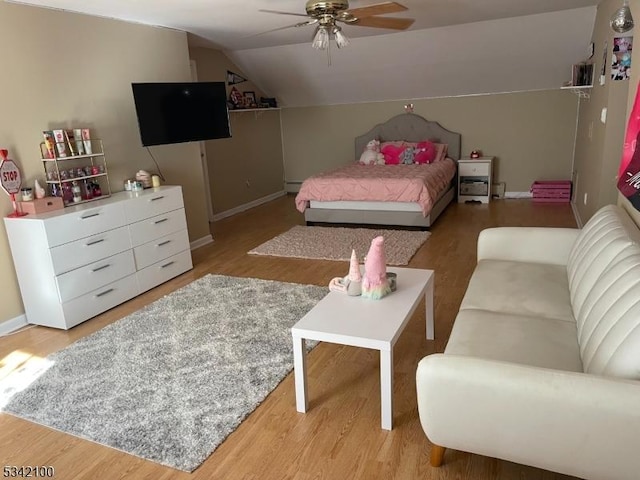 bedroom with light wood-type flooring, baseboards, vaulted ceiling, and a ceiling fan