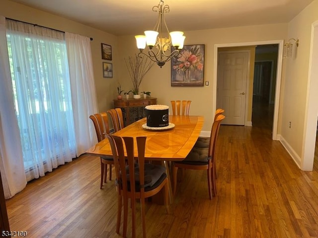 dining area featuring a notable chandelier, baseboards, and wood finished floors