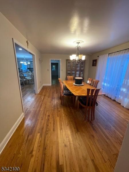 dining space with a chandelier, wood finished floors, and baseboards