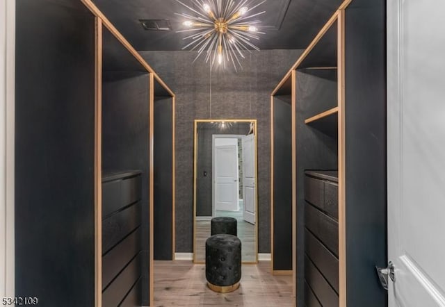 walk in closet featuring a notable chandelier, visible vents, and wood finished floors