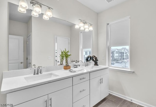 bathroom with double vanity, tile patterned flooring, a sink, and baseboards