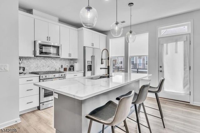 kitchen featuring tasteful backsplash, an island with sink, appliances with stainless steel finishes, a kitchen breakfast bar, and a sink