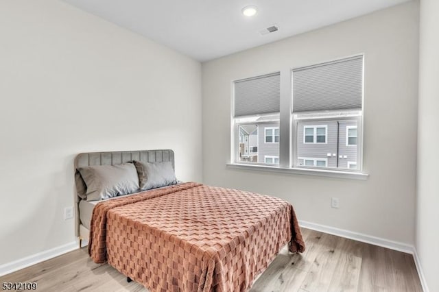 bedroom featuring visible vents, baseboards, and wood finished floors