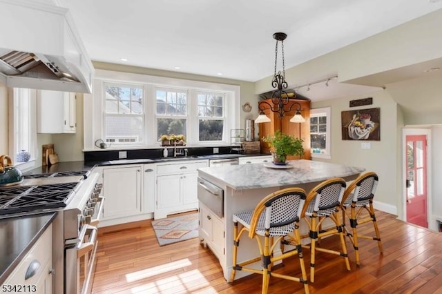 kitchen featuring light wood-type flooring, premium range hood, range with two ovens, and a center island