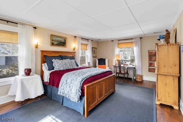 bedroom featuring multiple windows, ornamental molding, and dark wood-type flooring