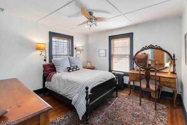 bedroom with a ceiling fan, radiator, visible vents, and wood finished floors