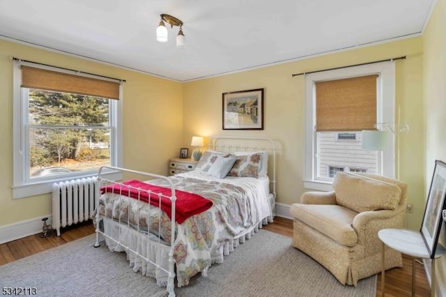 bedroom featuring radiator heating unit, baseboards, and wood finished floors