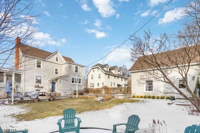 snow covered back of property featuring a yard