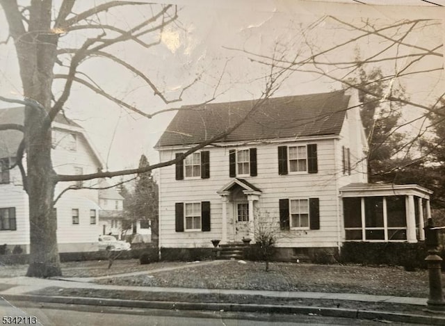 colonial house featuring a shingled roof and a sunroom