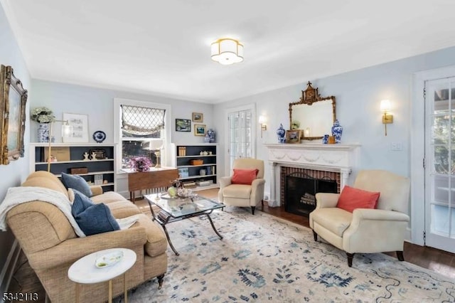 living area with a brick fireplace and wood finished floors