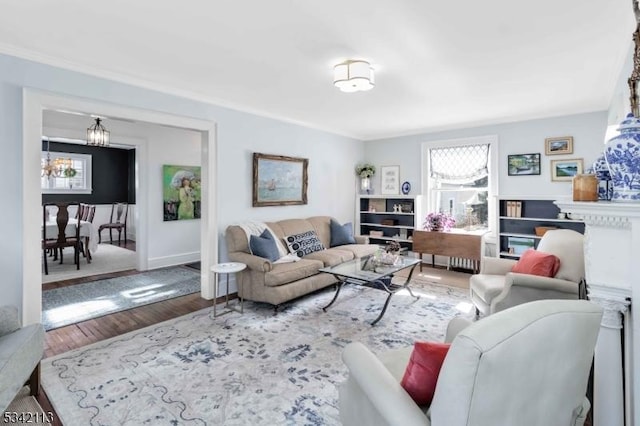 living room with an inviting chandelier, crown molding, and wood finished floors