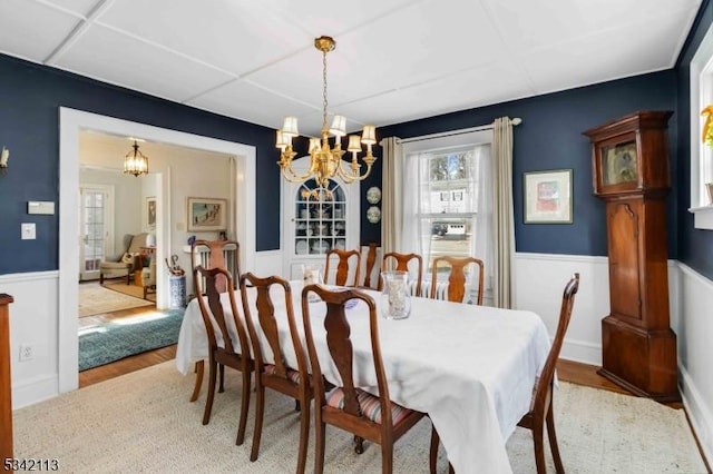 dining area featuring a wainscoted wall, light wood finished floors, and an inviting chandelier