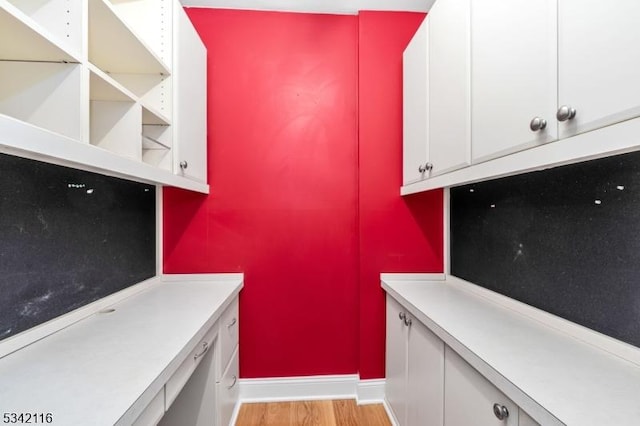 interior space with baseboards, white cabinetry, light wood-style flooring, and light countertops