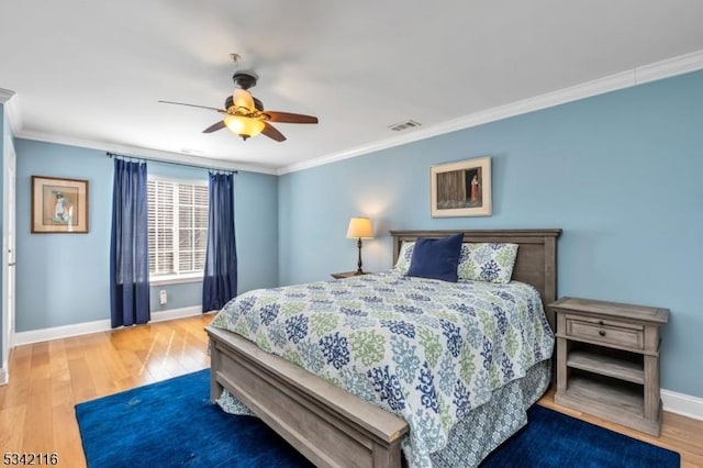 bedroom featuring visible vents, a ceiling fan, wood finished floors, crown molding, and baseboards