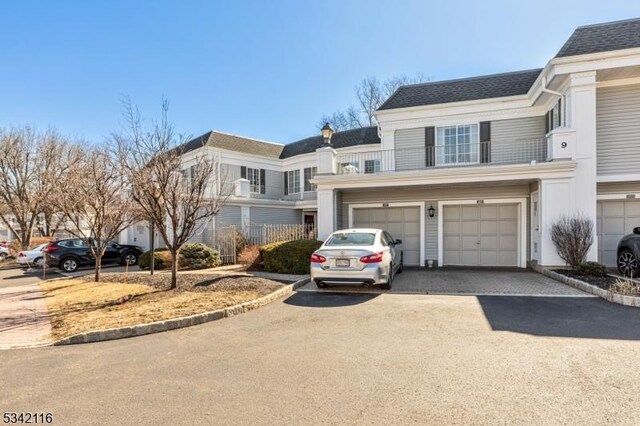 view of front of house featuring aphalt driveway, roof with shingles, and an attached garage