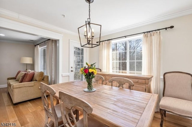 dining space with baseboards, light wood-type flooring, a chandelier, and ornamental molding