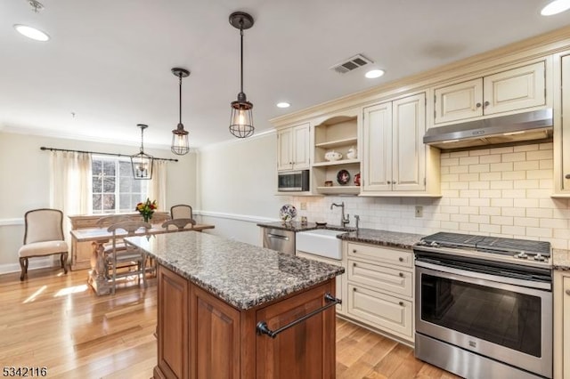 kitchen with under cabinet range hood, visible vents, appliances with stainless steel finishes, and cream cabinets