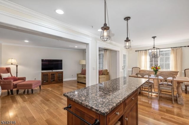 kitchen with decorative light fixtures, light wood-style floors, open floor plan, and crown molding