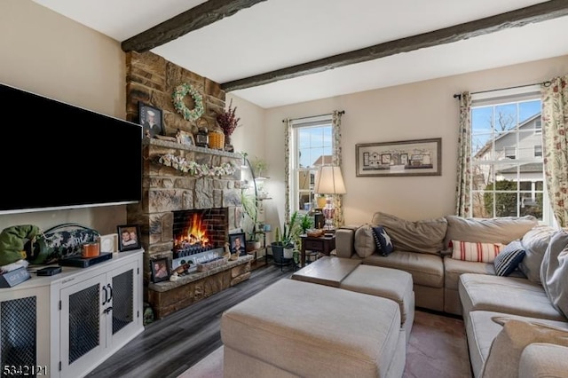 living room featuring a wealth of natural light, beamed ceiling, and a stone fireplace