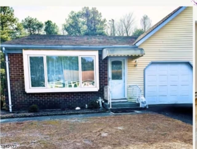 view of front of home with entry steps, brick siding, and an attached garage