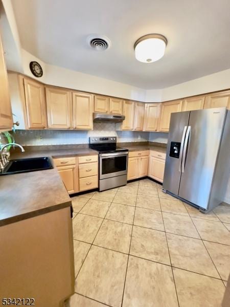 kitchen featuring visible vents, stainless steel appliances, under cabinet range hood, light brown cabinets, and a sink