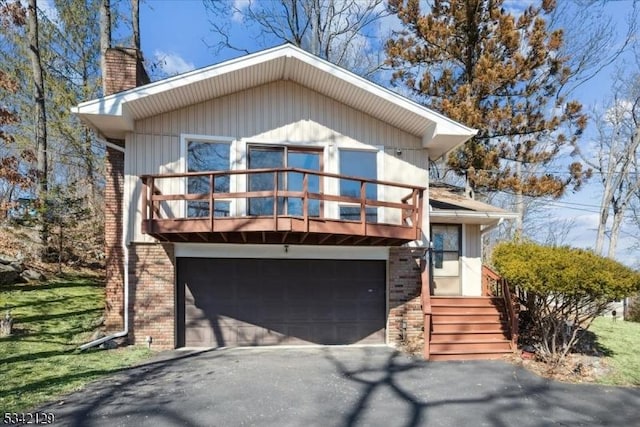 view of front of property with brick siding, driveway, a chimney, and a balcony