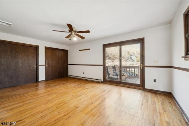 unfurnished bedroom featuring a baseboard heating unit, visible vents, access to exterior, light wood-type flooring, and two closets