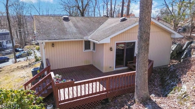 back of property with a shingled roof and a wooden deck