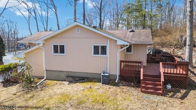 rear view of property with a garage, a wooden deck, and central AC unit