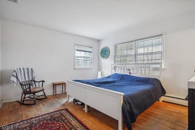 bedroom with baseboard heating and wood finished floors