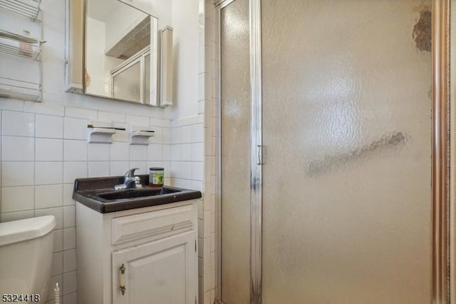 full bath with toilet, a stall shower, tile walls, and vanity
