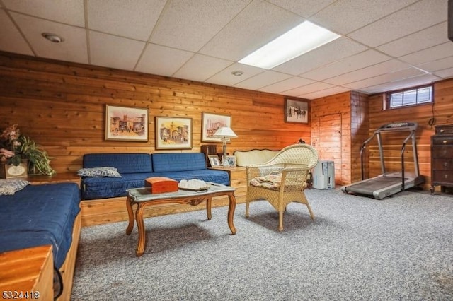 carpeted living area featuring a paneled ceiling and wood walls