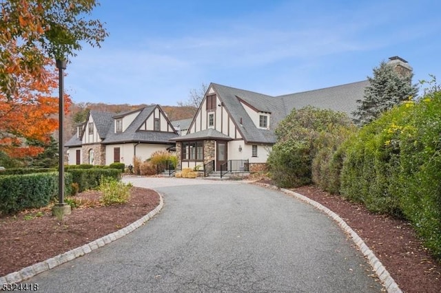 tudor house featuring stone siding, driveway, and stucco siding