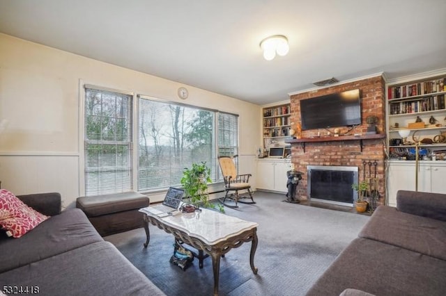 living area with visible vents, built in features, a wainscoted wall, carpet, and a fireplace