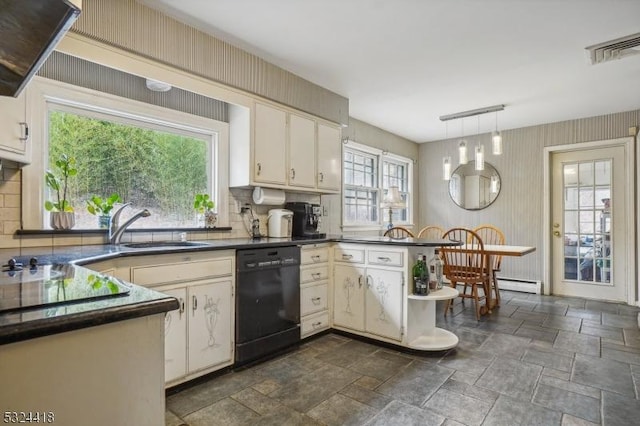 kitchen with dark countertops, stone finish flooring, a sink, dishwasher, and a peninsula