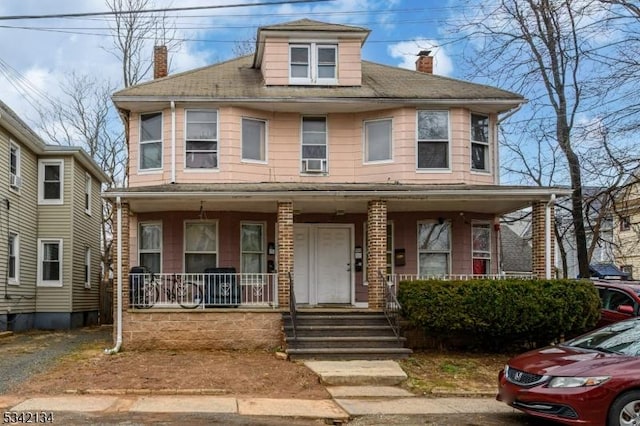 traditional style home featuring covered porch and a chimney