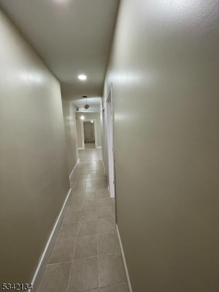 hallway featuring tile patterned flooring and baseboards