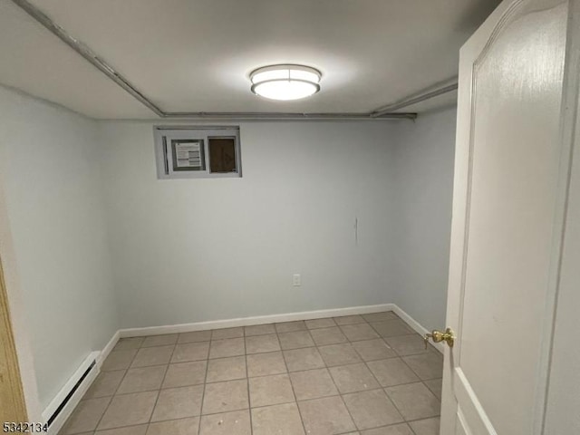 finished below grade area with light tile patterned flooring, baseboards, and a baseboard radiator