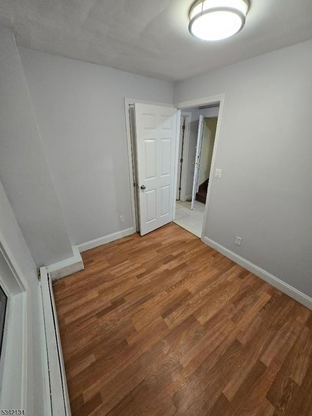 spare room featuring light wood-type flooring and baseboards