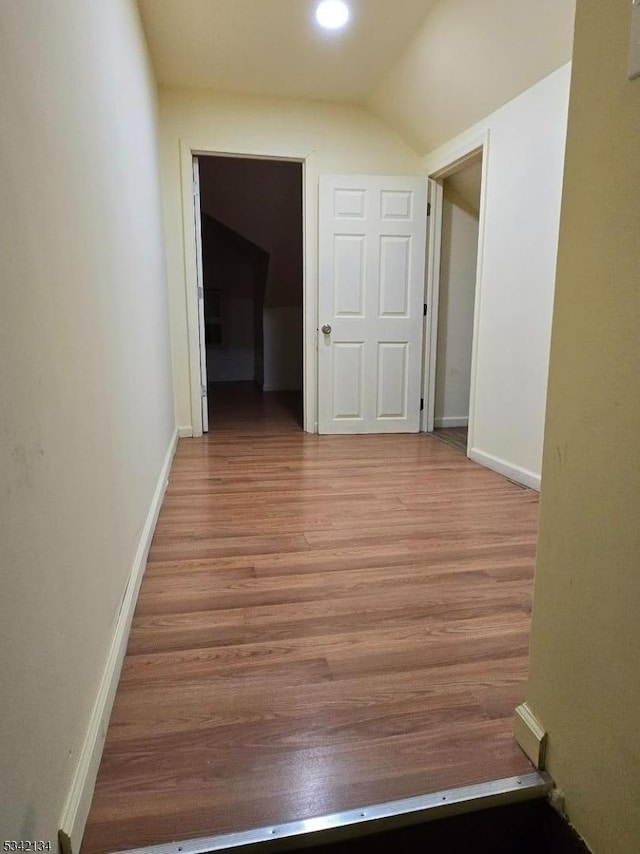 corridor featuring light wood-style flooring and baseboards