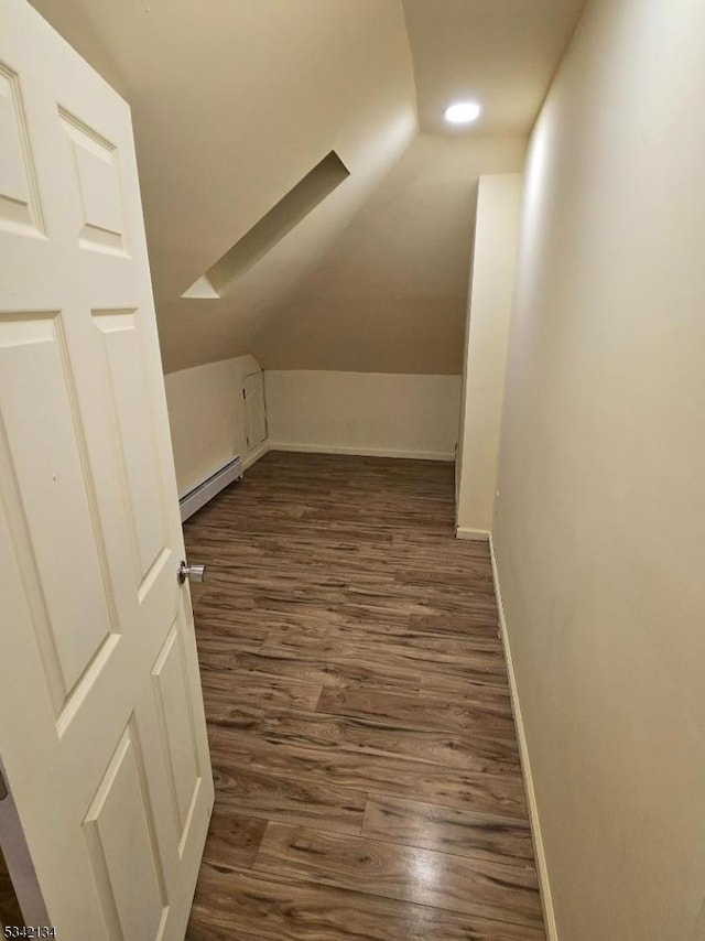 additional living space featuring dark wood finished floors, baseboard heating, baseboards, and lofted ceiling